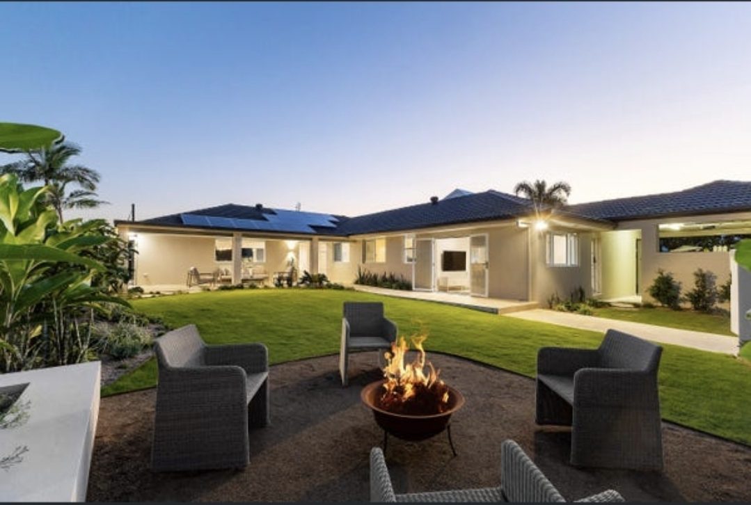 The same backyard finished with lawn, a fire pit and outdoor seating at dusk