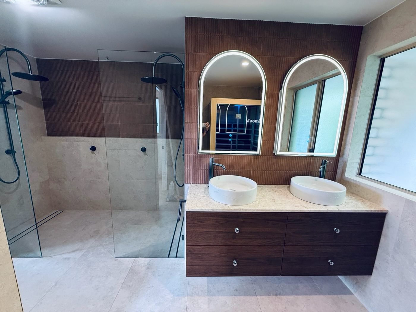 Renovated bathroom with walk-in double shower and twin arched LED mirrors