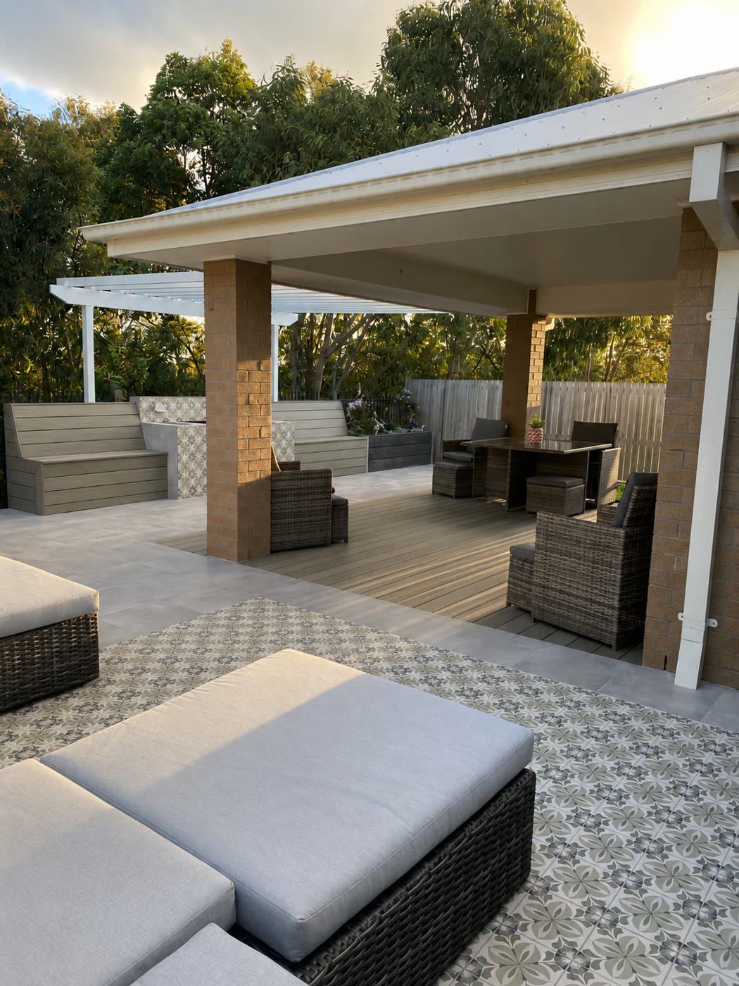 Covered alfresco with brick pillars, composite deck, patterned feature tiles and built-in bench seating