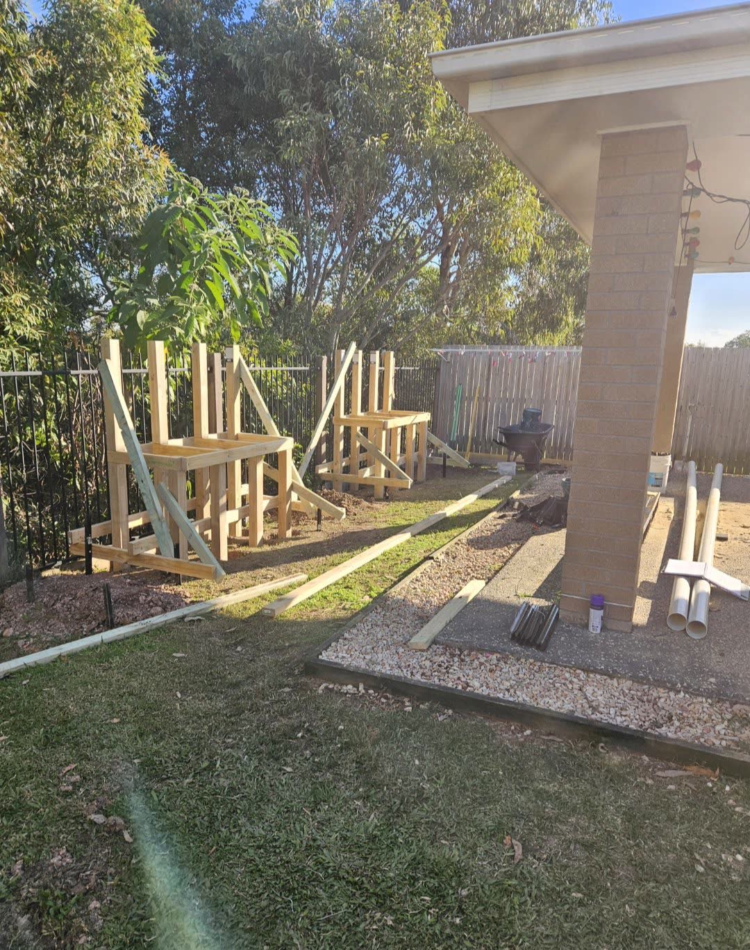 Timber framing for built-in bench seating going up along the fence line